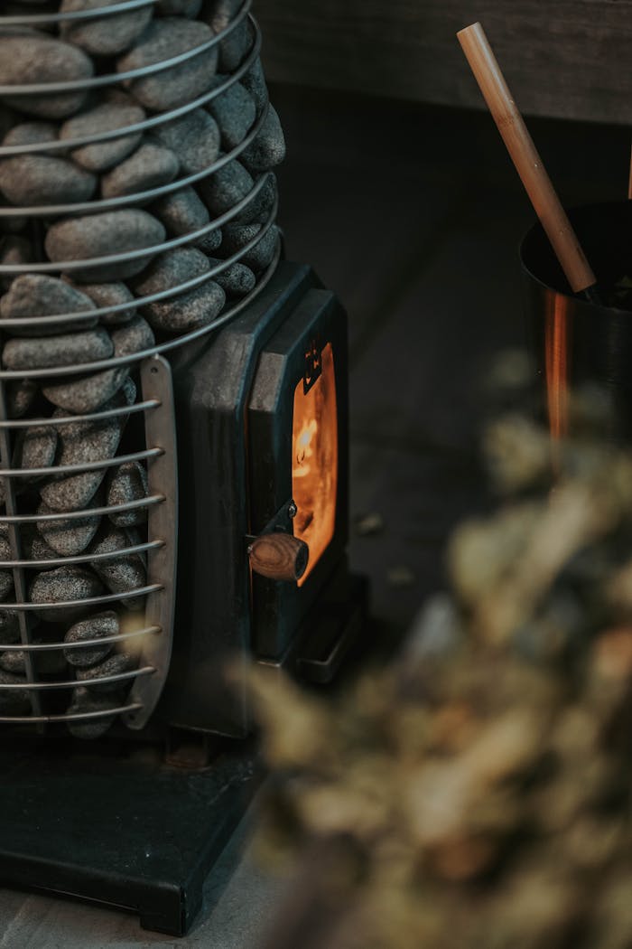 Warm ambiance with a sauna stove and stone heater creating a cozy firelight atmosphere.