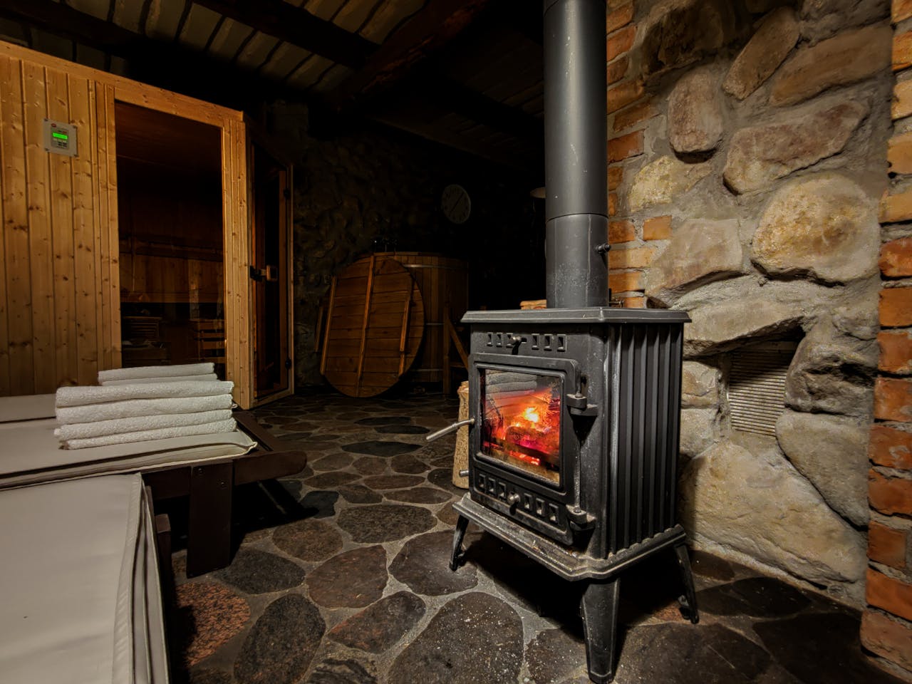 Warm sauna room in Płociczno featuring a classic wood-burning stove and rustic stone walls.