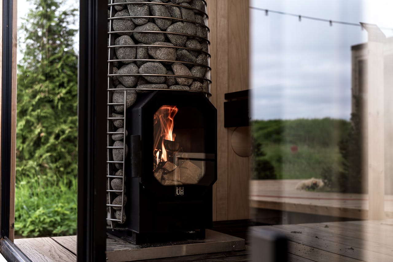 A stylish sauna interior featuring a modern stone heater with a view of lush greenery.